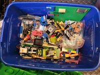 Top view of blue bin filled with mixed LEGO pieces, baseplate and bags