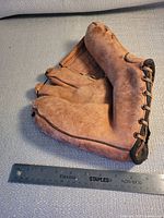 Full view of three-finger glove beside 12-inch ruler showing size and leather lacing