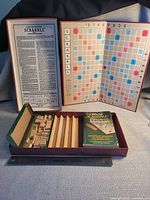Open Scrabble box displaying folding board, rules, racks, tiles, dictionary