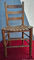 Full frontal view of wooden ladder-back chair showing overall design and condition
