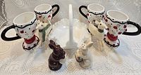 Group shot of four mugs, milk glass dish, two deer, two rabbit figurines