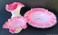 Front view of vase, small bowl, and oval dish displaying ruffled clear rims and pink interiors.
