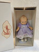 Kewpie doll in box showing full outfit and stand