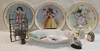 Front view of plates, serving dish, owl figurines, metal rack with plant and candle holder