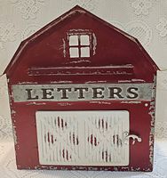 Front view showing red barn shape, LETTERS plaque, white barn door closed