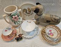 Group shot showing all items: cups, saucers, pitcher, plate, wooden dog box, cherub figurine