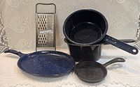 All items: grater, enamel griddle, nested enamel pans, mini cast iron skillet