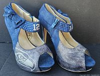 Shoes front and side view showing logo, glitter toe, bow, embroidered 12