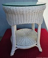Full view of white wicker round table with glass top and lower shelf