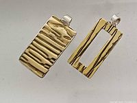 front view showing brass textured faces of both pendants
