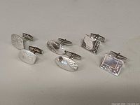 All three pairs of cufflinks lined side by side on neutral background