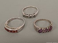 Three sterling silver rings laid out showing stone colors and designs
