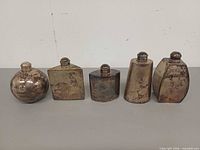 Front view of all five flasks showing shapes and tarnish