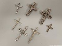 All seven silver-tone cross and crucifix pendants displayed