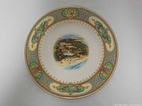 Top view of entire dinner plate showing central scene, fish border and crest