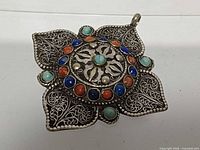 Front view of silver filigree pendant showing overall design and stone layout