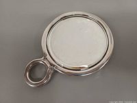 Front view of round sterling silver hand mirror showing face and handle