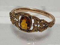 Front view showing ornate scroll setting and amber stone