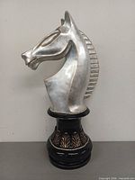 Front-left view of silver resin horse head chess statue on black pedestal