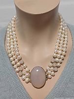 Necklace on display bust showing four strands of pearls and agate pendant
