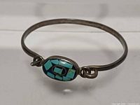 Full view of bracelet showing oval turquoise inlay centerpiece and overall form