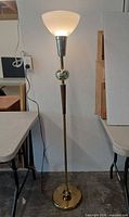 Full view of lit torchiere floor lamp showing materials and design