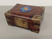 Top and front view showing brass latch, corner mounts and cloisonné medallion