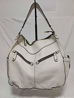 front view showing overall style, dual front zip pockets, strap