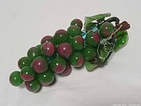 Front view of green and purple glass grape cluster with leaves
