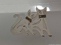 Front view of brooch showing twin cats design and brass bows