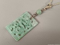 Front view of carved jadeite pendant, bead, and part of chain