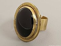 Front view of ring showing black glass cabochon and metal bezel