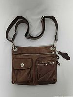 Front view showing overall bag, strap, pockets, hardware