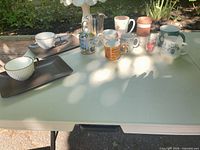 Overview of all mugs, teacups, trays and pitcher on table