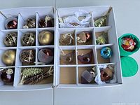 Two compartmented trays filled with assorted ornaments and green tin