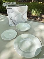 Box of Stokes Spiral White 12-piece dinnerware set with three pieces displayed