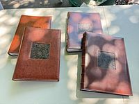 Four brown faux leather albums with rectangular patterned inlays displayed on table