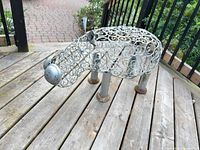 Side view of metal scrollwork hippopotamus sculpture on wooden deck