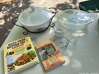 All items laid out: ceramic casserole in stand, glass baker, two ramekins, two glass bowls, two books