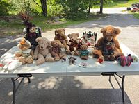 Entire lot of plush animals, clothing pieces and accessories displayed on table outdoors