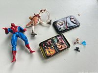 Group shot showing Spider-Man figure, Star Wars creature, tin with playing cards and loose accessories