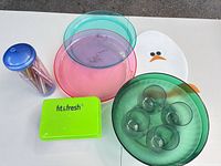 All items grouped: food container, plates, green bowl holding glasses, straw tube