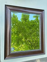 Front view of mirror showing brown wood-look frame and reflection
