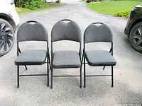 Front view of all three folding chairs standing side by side on driveway