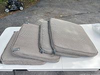 Stack of four woven cushions on table showing top surfaces