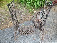 Full view of Singer cast iron treadle base showing pedal, flywheel and side frames