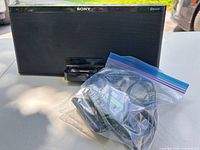 Front view of Sony speaker dock with power adapter and remote in bag