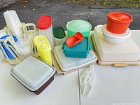 overview of assorted Tupperware containers, tumblers in beige holder, scoops, stackable boxes