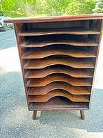 Front view showing eight curved shelves and tapered legs