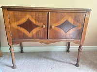 Front view of solid wood 2-door sideboard showing diamond inlay panels, knobs, turned legs